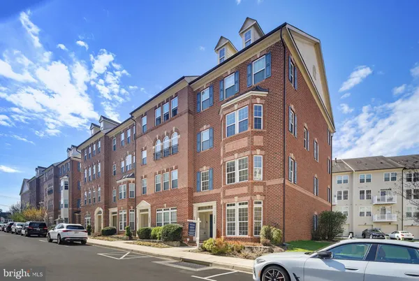 a front view of a building with lot of cars and trees