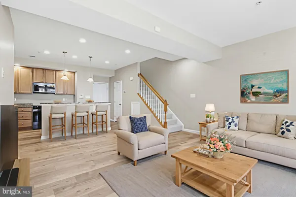 a living room with furniture kitchen view and a wooden floor
