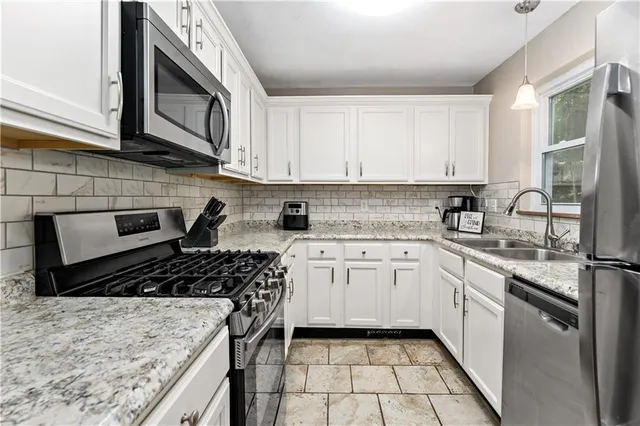 a kitchen with stainless steel appliances granite countertop a stove a sink and a microwave