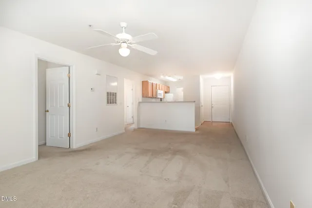 an empty room with a kitchen and a chandelier fan