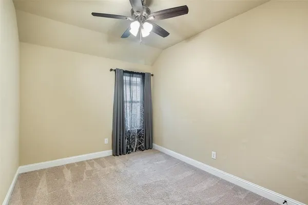 an empty room with a chandelier fan and windows