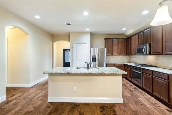 a large kitchen with kitchen island granite countertop wooden cabinets a granite counter tops and a stove