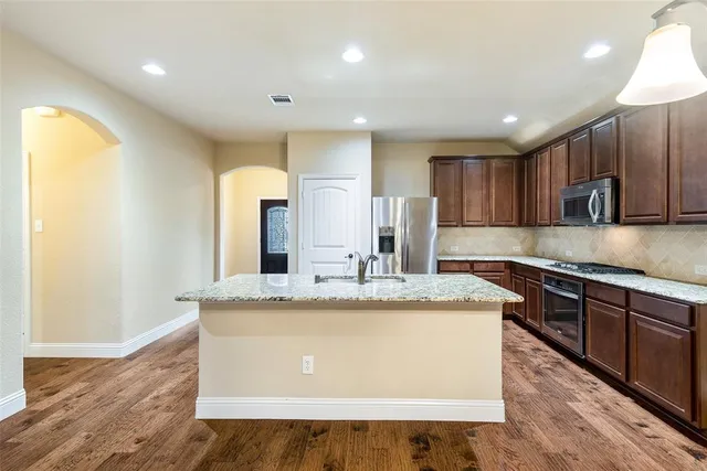 a large kitchen with kitchen island granite countertop wooden cabinets a granite counter tops and a stove