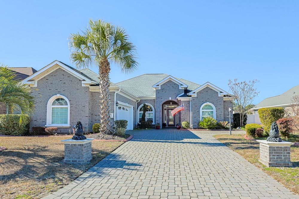View of front facade featuring decorative driveway, a garage, and brick siding
