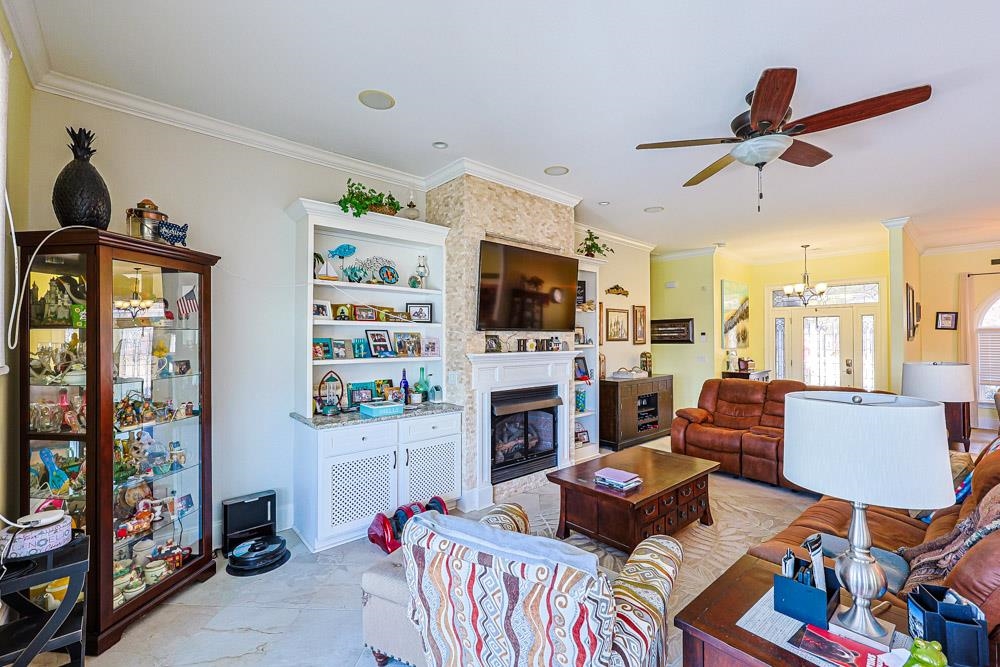 232 Waterfall Circle Little River, SC 29566 - Photo 8 of 40 Living room featuring ornamental molding, a large fireplace, a chandelier, and a ceiling fan