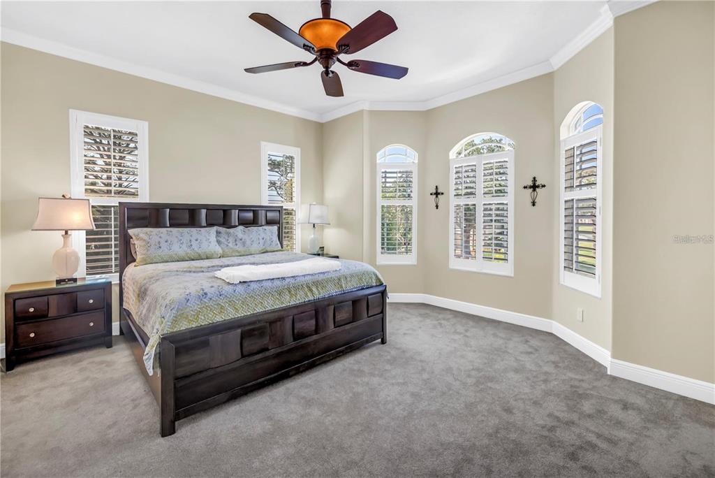 2101 North Pointe Alexis Drive, Unit 1 Tarpon Springs, FL 34689 - Photo 7 of 63 a spacious bedroom with a balcony a bed and a chandelier