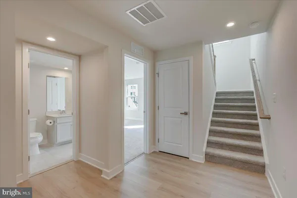 a large kitchen with stainless steel appliances granite countertop a refrigerator a sink a stove and white cabinets with wooden floor