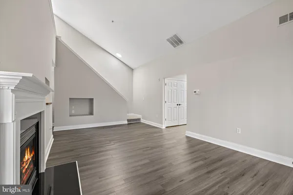 a view of an empty room with wooden floor and a fireplace