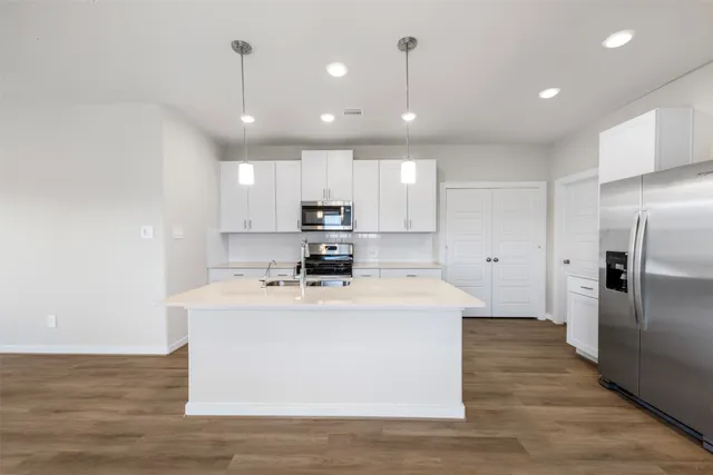 a large kitchen with stainless steel appliances granite countertop a sink a stove and a refrigerator