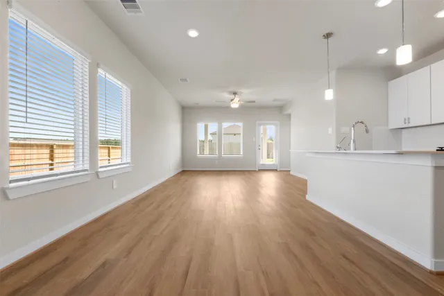a view of an empty room with window and wooden floor