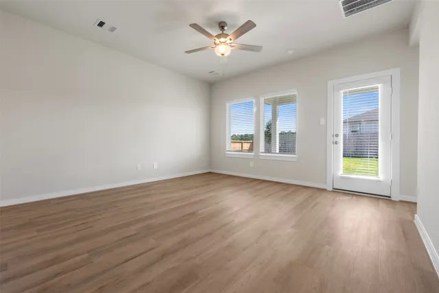 a view of an empty room with a window and wooden floor
