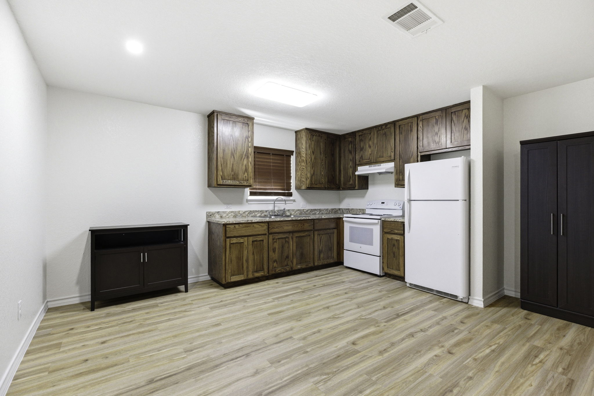 823 North Commerce Street, Unit A Lockhart, TX 78644 - Photo 9 of 28 a kitchen with a refrigerator sink and wooden cabinets