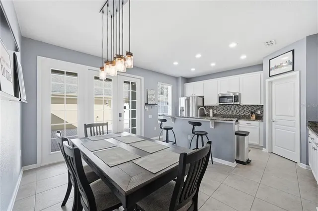a dining room with stainless steel appliances kitchen island granite countertop a dining table chairs and a refrigerator