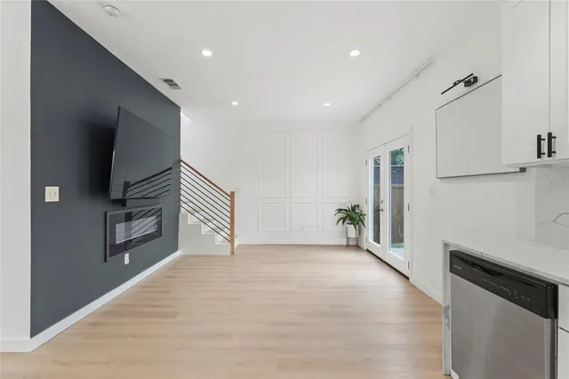 a view of an empty room with a window and wooden floor