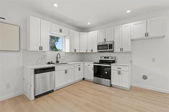 a kitchen with granite countertop white cabinets and stainless steel appliances