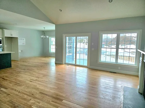 a view of an empty room with window and wooden floor