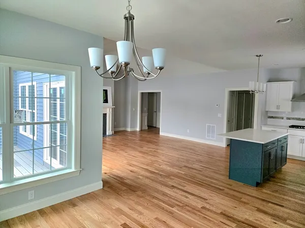 a view of an empty room with wooden floor and windows