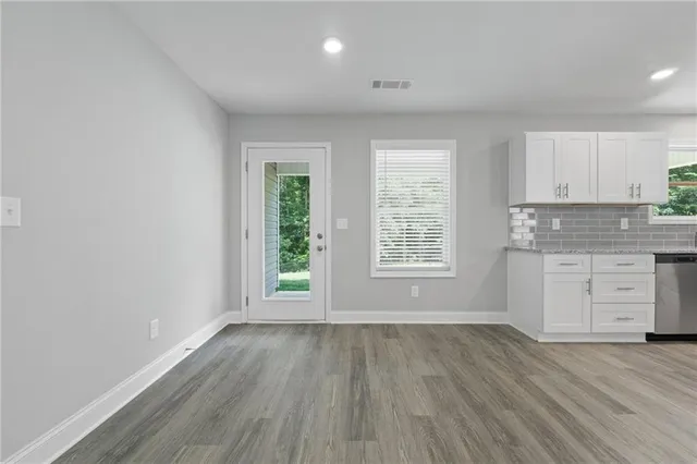 an empty room with wooden floor and windows