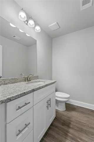 a bathroom with a granite countertop toilet sink and mirror