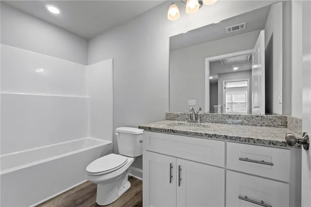 a bathroom with a granite countertop toilet a sink and a mirror