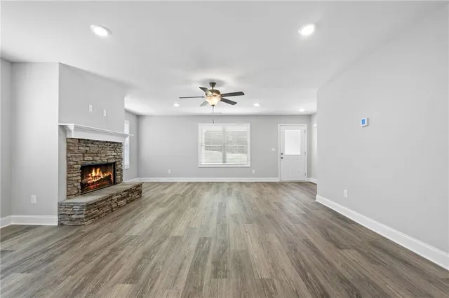 an empty room with wooden floor fireplace and window