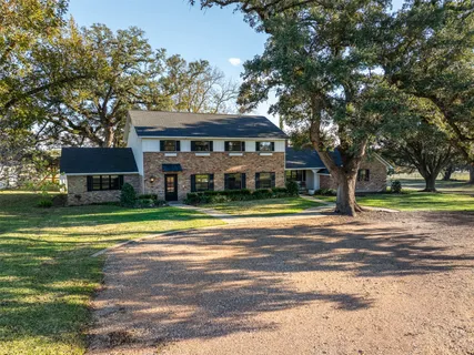 a view of a house with a big yard and large trees