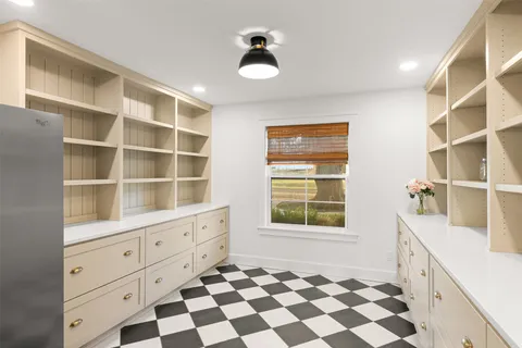 a room with a black white checkered floor and a large window