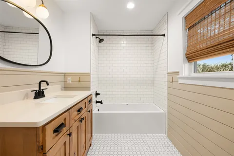 a bathroom with a sink a vanity a mirror and a bathtub