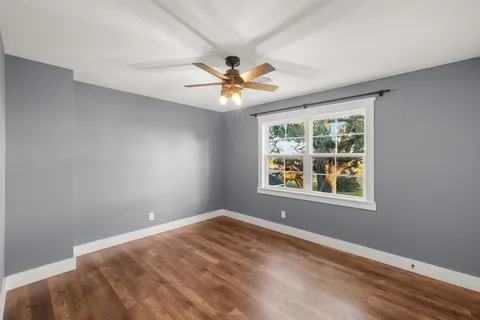 an empty room with windows and chandelier fan