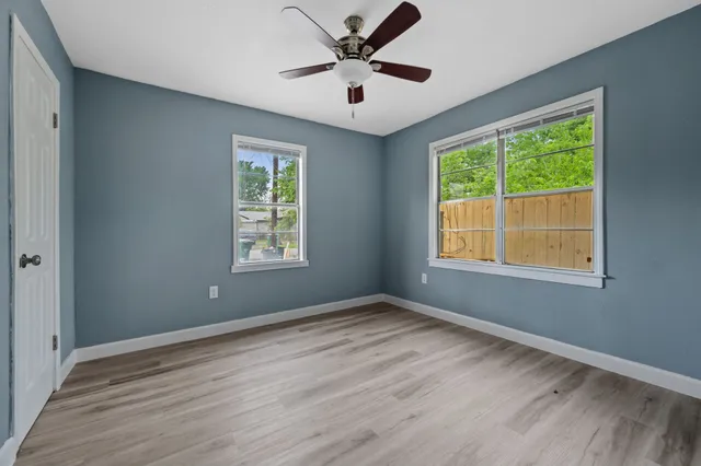 a view of an empty room with wooden floor and a window