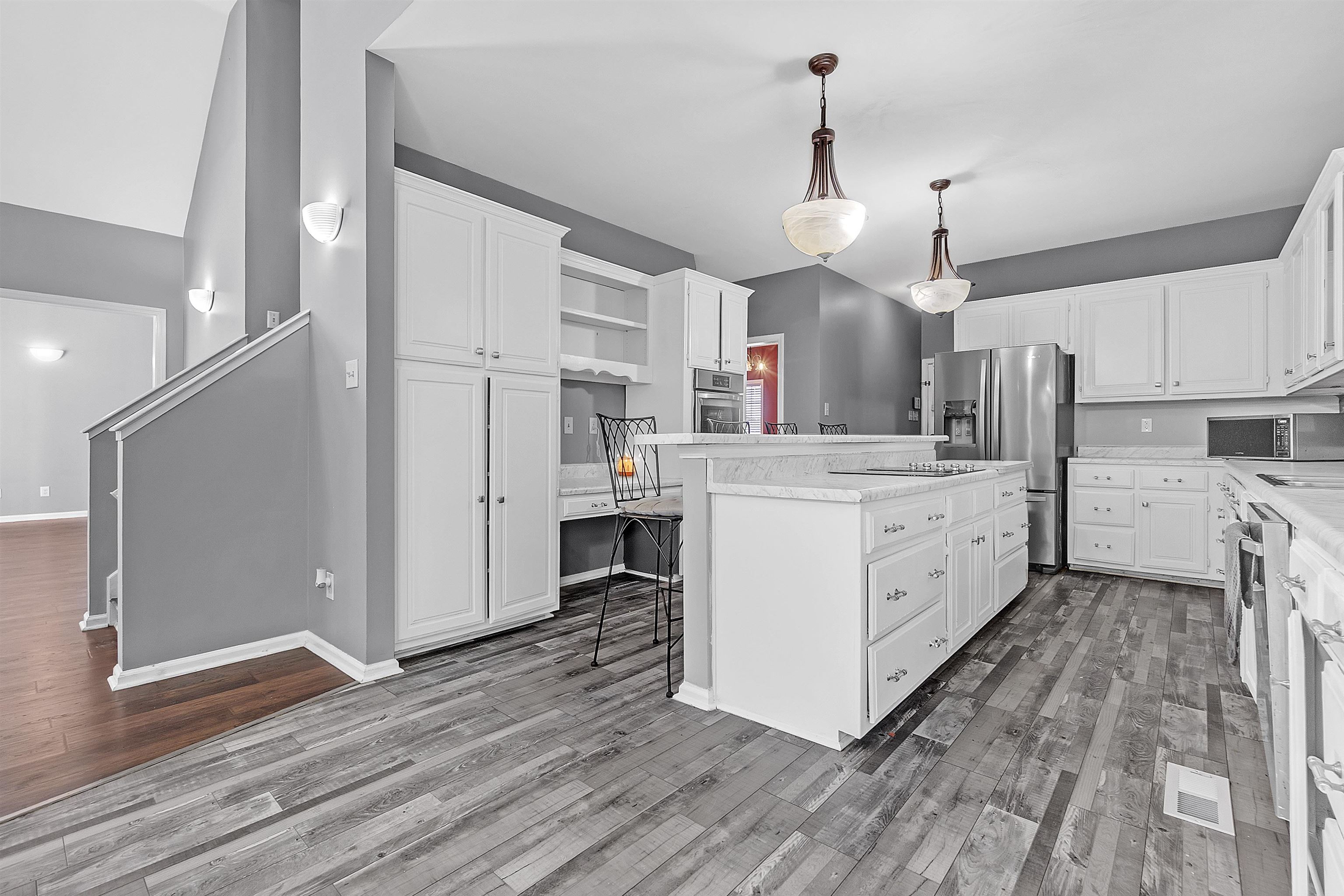 4366 Campground Road Munford, TN 38058 - Photo 11 of 40 Kitchen with a multi-functional island that includes a cooking surface, breakfast bar, white cabinets, open shelves, stainless steel appliances, pendant lighting, and a pantry cabinet