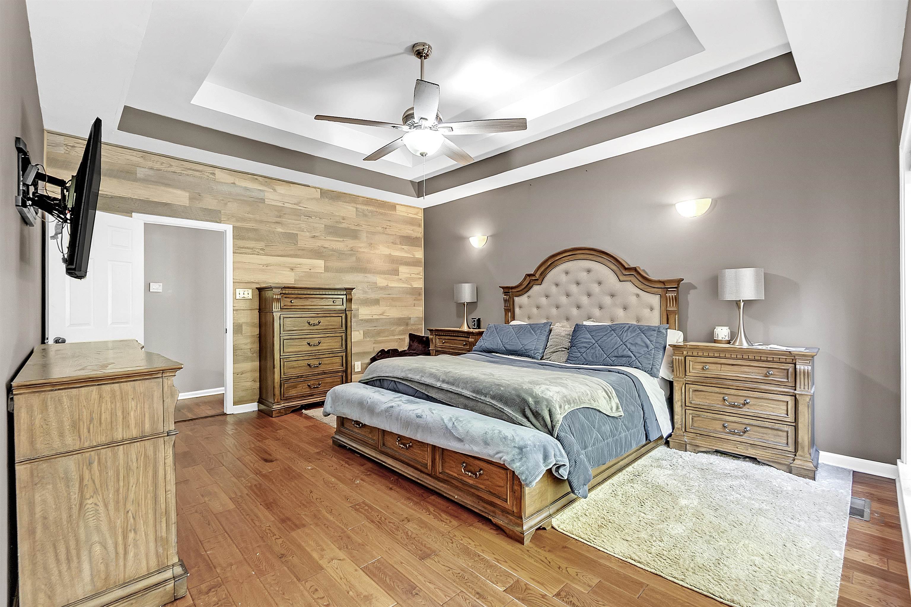 4366 Campground Road Munford, TN 38058 - Photo 17 of 40 Bedroom featuring a tray ceiling, wood walls, light wood-style flooring, and a ceiling fan