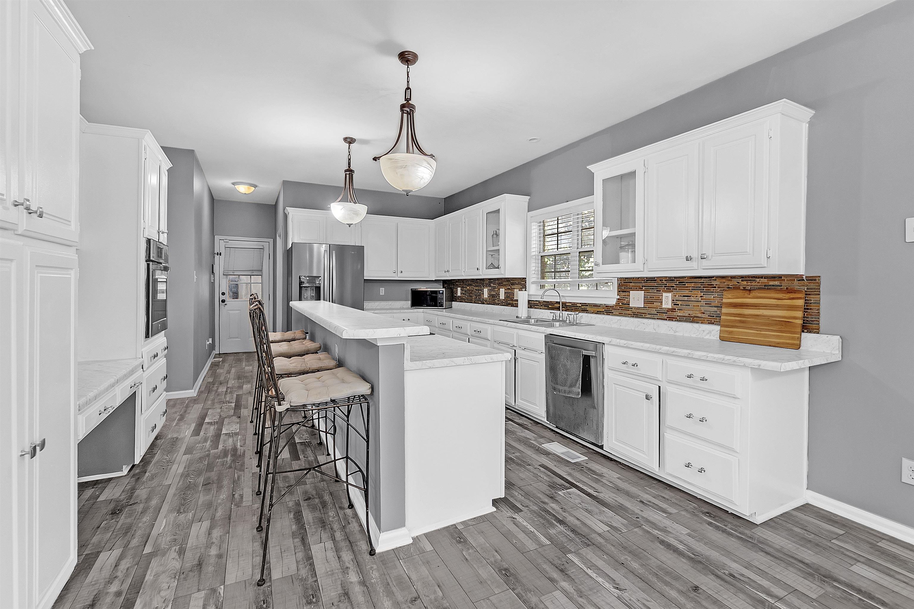 4366 Campground Road Munford, TN 38058 - Photo 10 of 40 Kitchen with a kitchen breakfast bar, decorative light fixtures, white cabinets, decorative backsplash, and stainless steel appliances