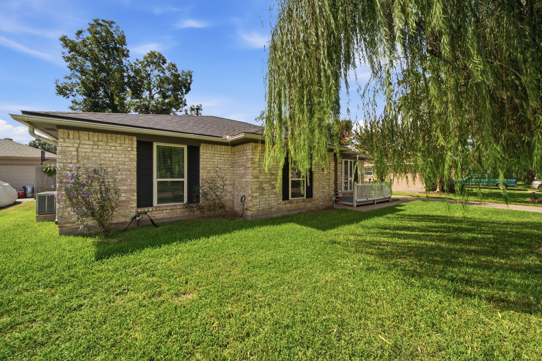 19519 Ricelake Lane Houston, TX 77084 - Photo 2 of 47 Charming brick home with lush green lawn, shaded by a beautiful weeping willow tree, offering a serene outdoor space.