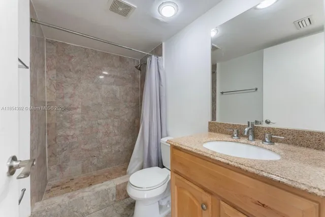 a bathroom with a granite countertop sink toilet and shower