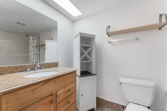 a bathroom with a granite countertop sink a toilet and a mirror