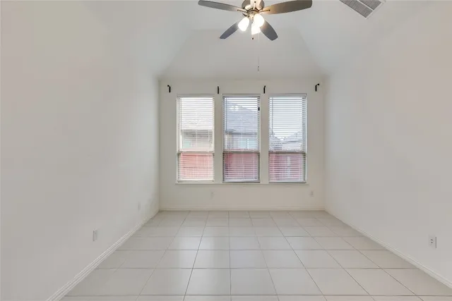an empty room with chandelier fan and windows