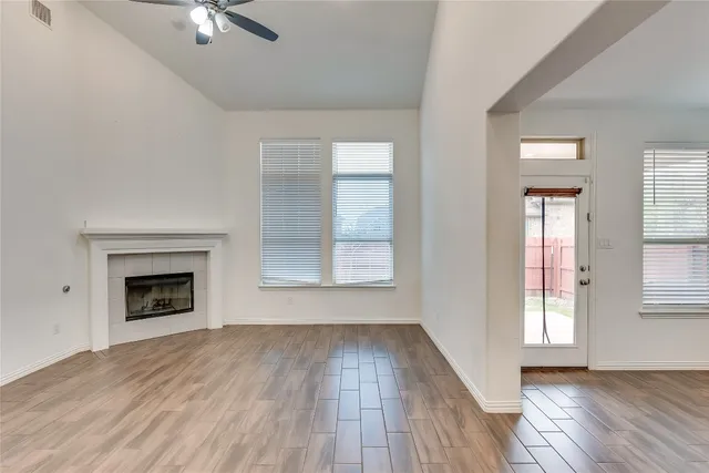 an empty room with wooden floor fireplace and windows