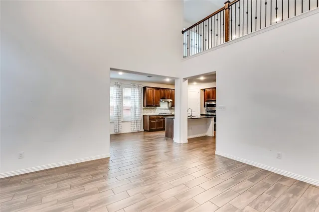 a view of a hallway with wooden floor and a kitchen