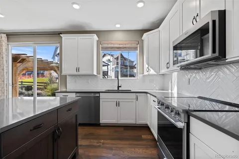 a kitchen with stainless steel appliances granite countertop a refrigerator a sink dishwasher a stove and white countertops with wooden floor
