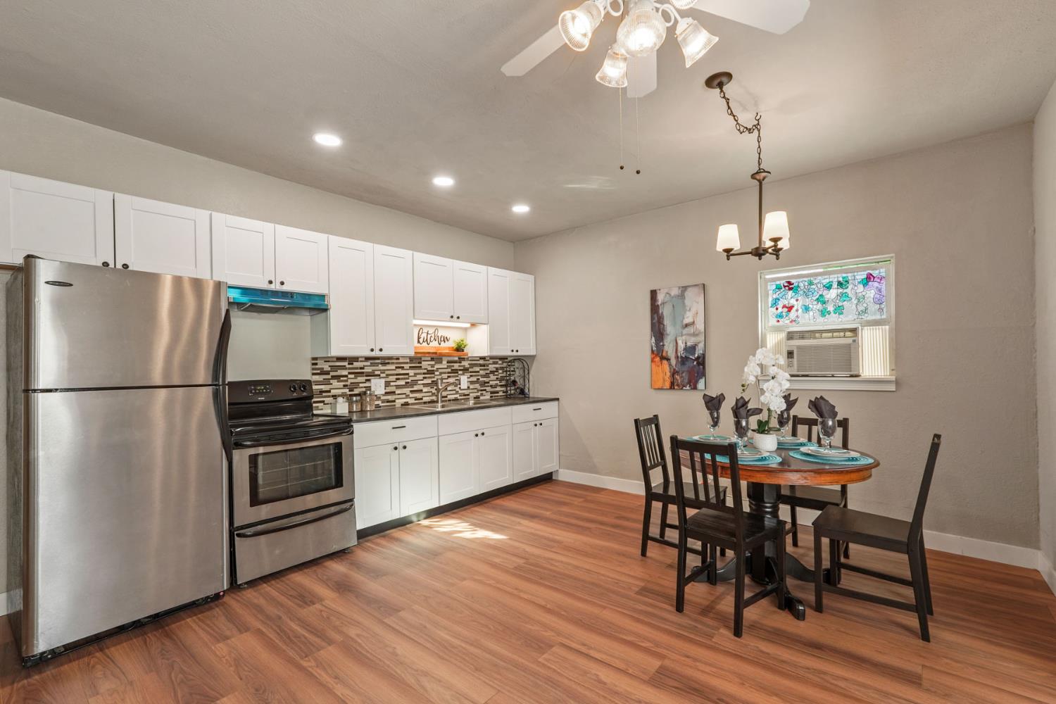 715 North Sutter Street Stockton, CA 95202 - Photo 38 of 51 a kitchen with stainless steel appliances granite countertop a refrigerator a stove a sink dishwasher a dining table and chairs with wooden floor