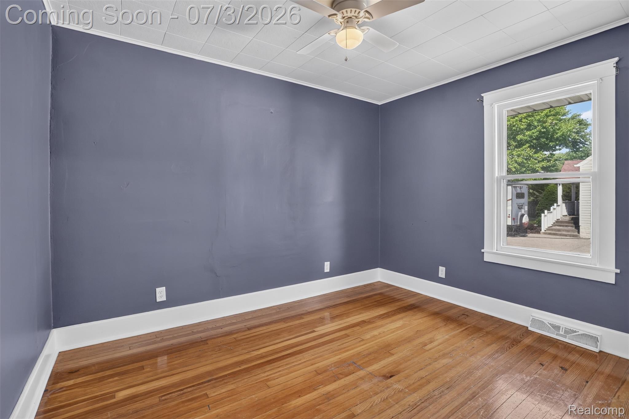 4322 Baker Road Bridgeport, MI 48722 - Photo 11 of 29 Hardwood flooring throughout featuring white trim, a ceiling fan with integrated lighting, and a window with white casing