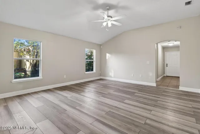 a view of an empty room with a window and wooden floor