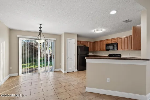 a view of a kitchen with a sink wooden cabinets and a window