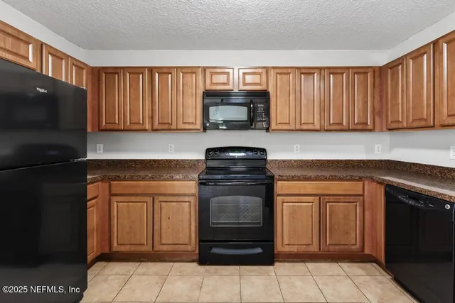 a kitchen with granite countertop a stove top oven microwave and cabinets