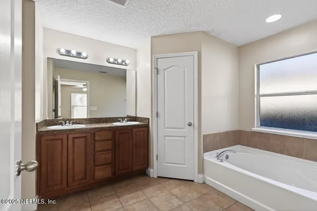 a bathroom with a tub a double vanity sink and mirror