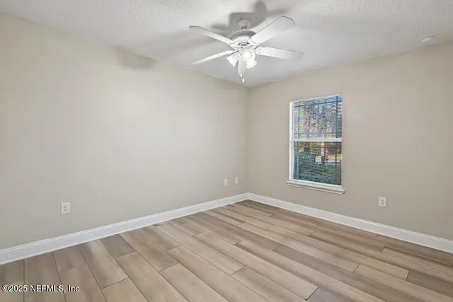 an empty room with a chandelier fan and windows