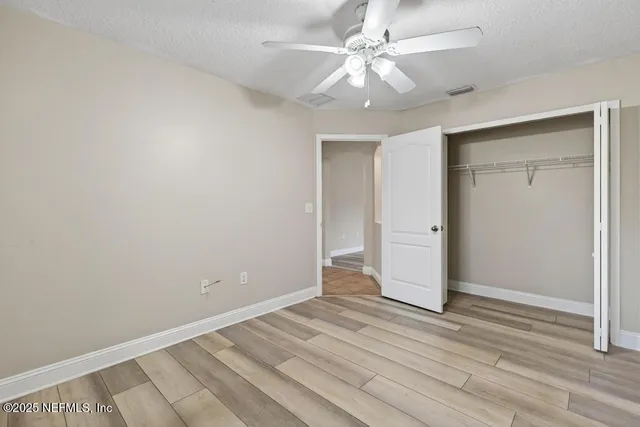 an empty room with wooden floor and ceiling fan