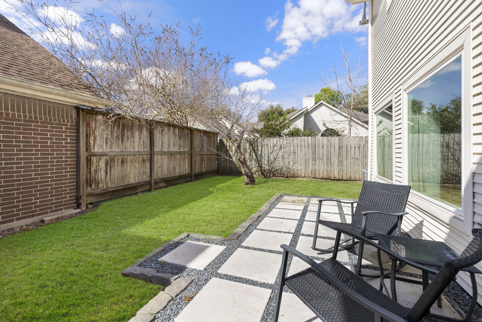 2110 Paso Rello Drive Houston, TX 77077 - Photo 36 of 41 This photo showcases a cozy backyard with a well-maintained lawn, a wooden fence for privacy, and a small patio area. The space is ideal for relaxing or entertaining, with ample natural light and privacy.