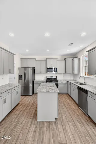 a large kitchen with a center island and stainless steel appliances